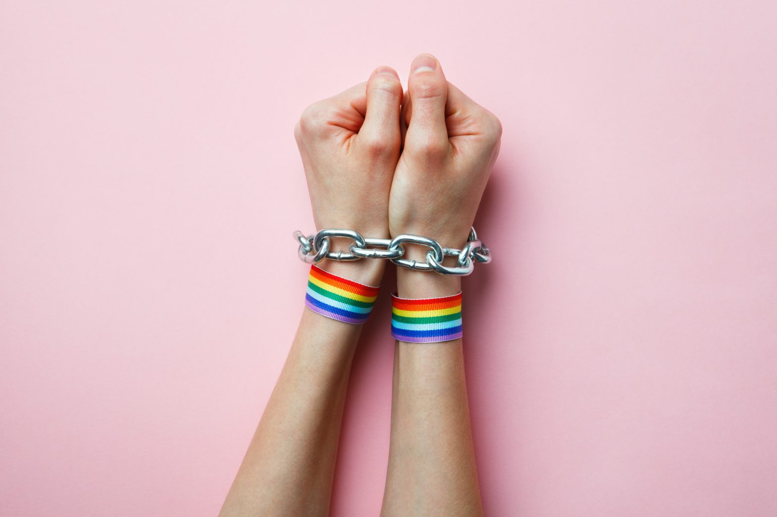 Hands with rainbow ribbon in chains, symbolizing incarcerated LGBTQ people. Washington State Department of Corrections - transgender prisoner