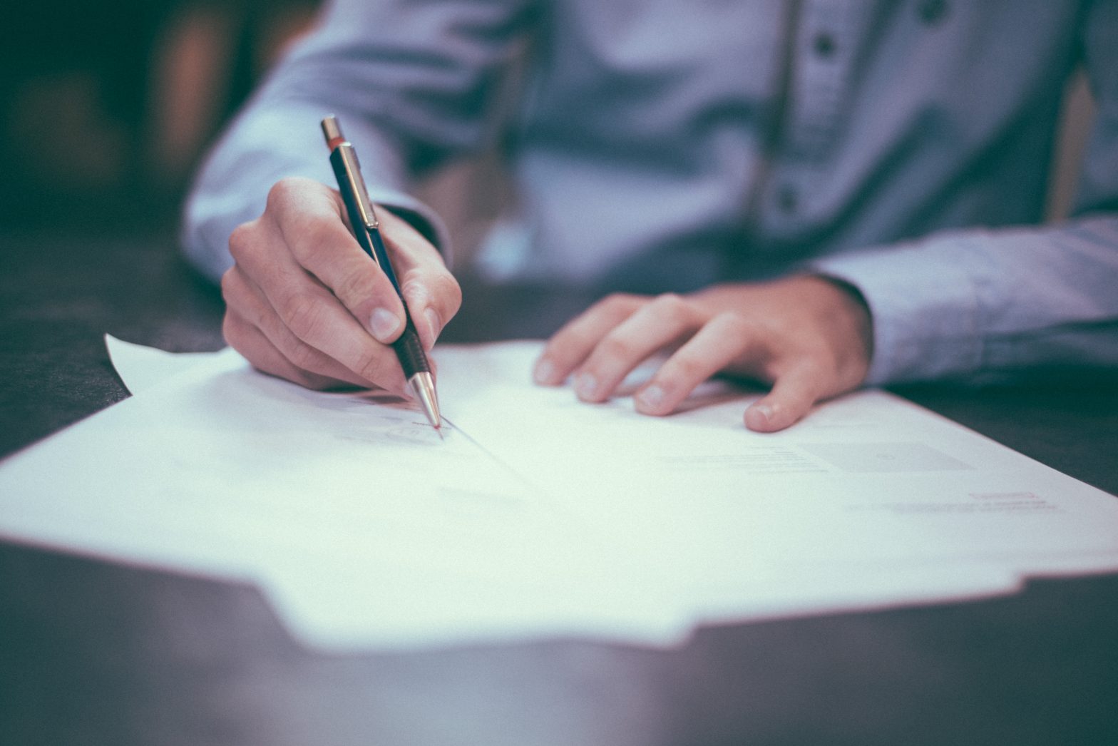 A man is signing documents. (juvenile justice facilities) Photo by Scott Graham on Unsplash