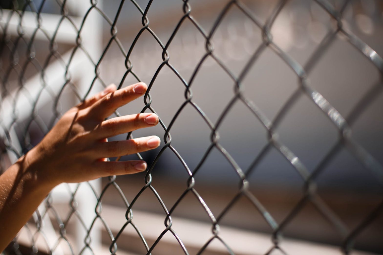 Hand of person touching grid fence. Echo Glen detention center