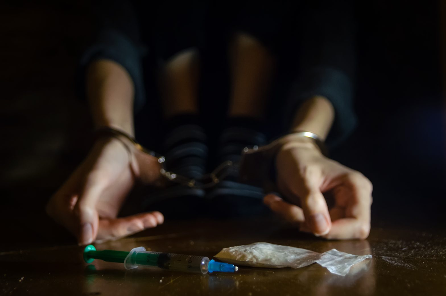Cuffed hands in front of illegal drugs. Jefferson Country jails
