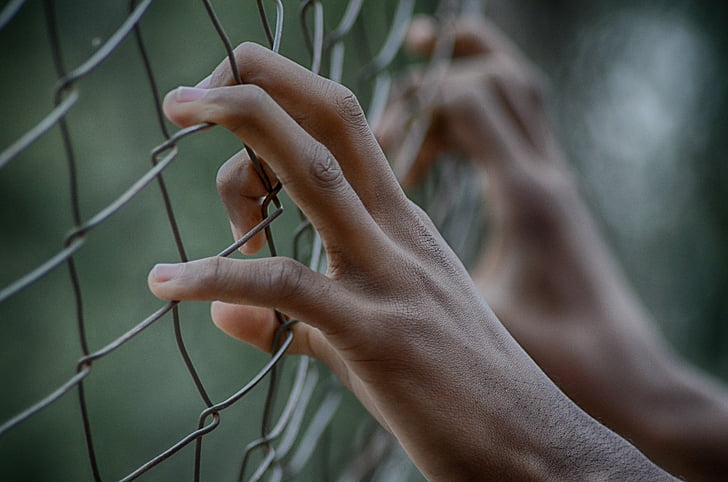 A pair of your hands are holding a fence. Juvenile Gregory Tompkins Faces Criminal Charges After Violent Detention Center Episode