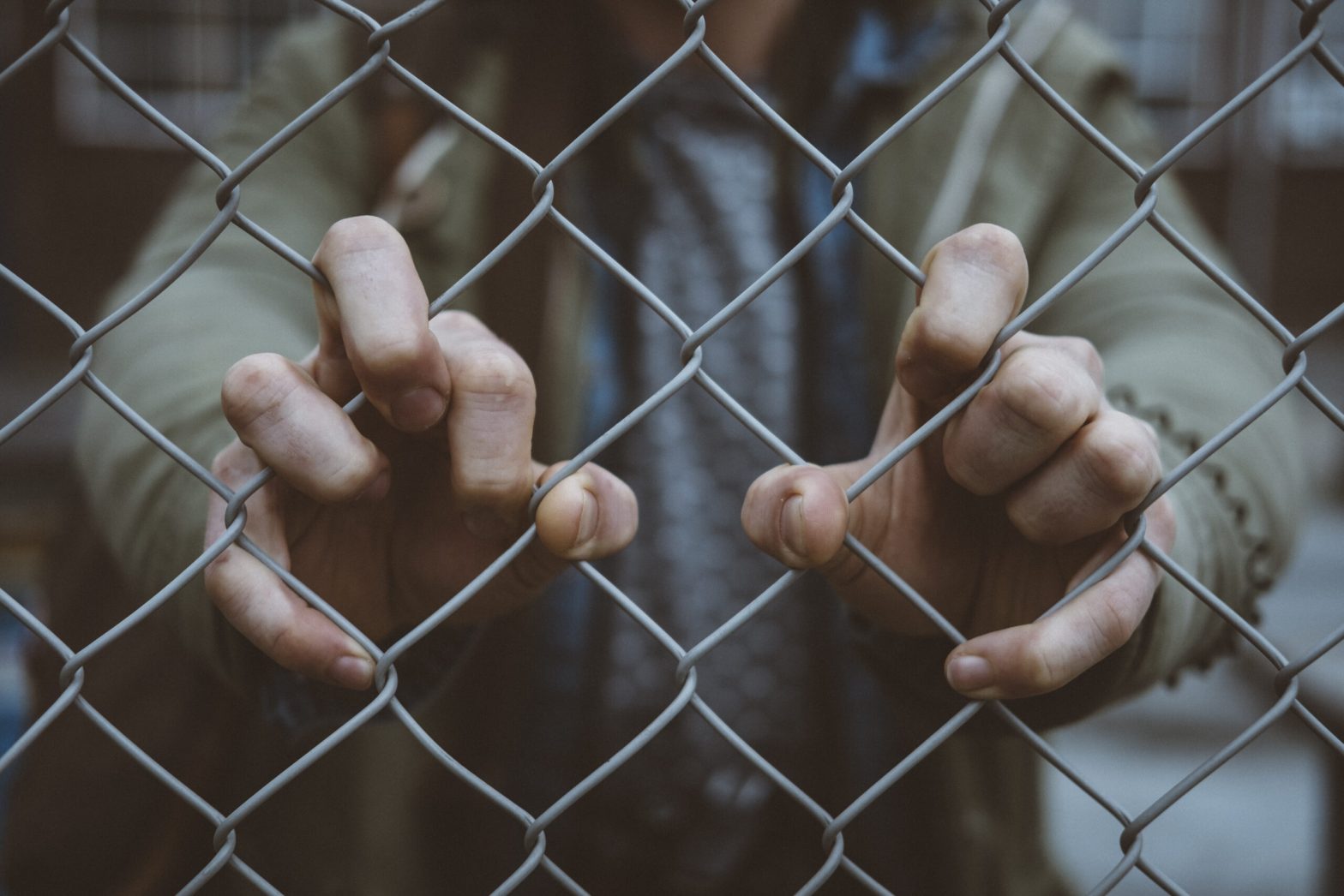 Macro view of an urban person's hand on a chain link fence. solitary confinement