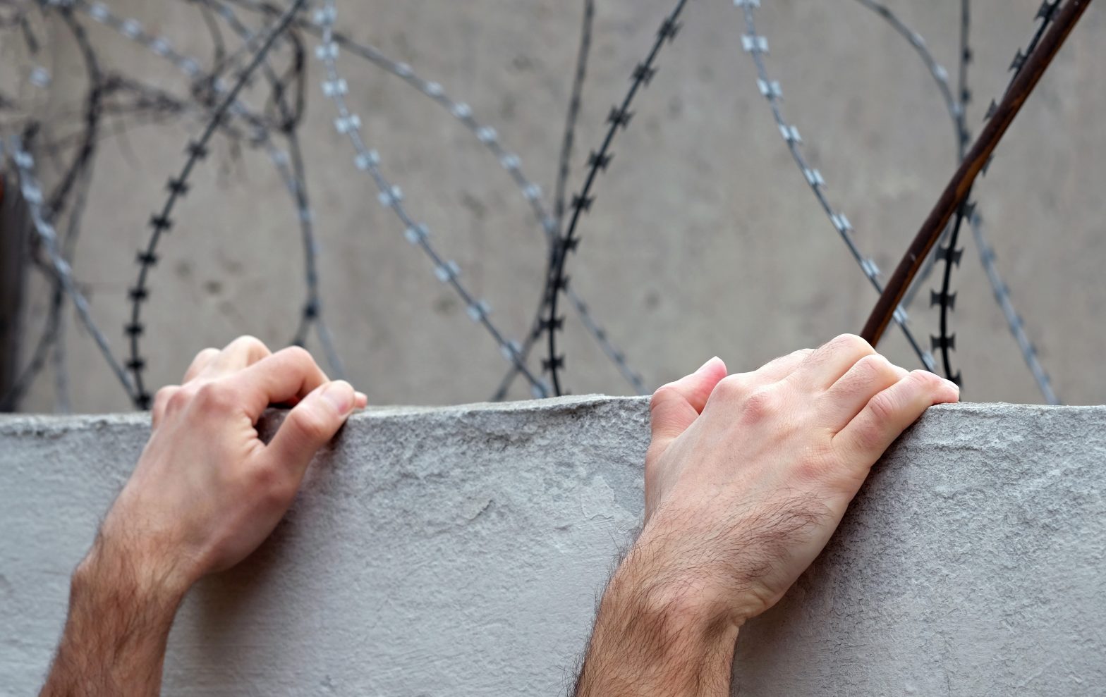 A pair of hands of a man trying to climb a fence. News - Dead body of Riverside Correctional Facility escapee Gino Hagenkotter found in Philadelphia warehouse