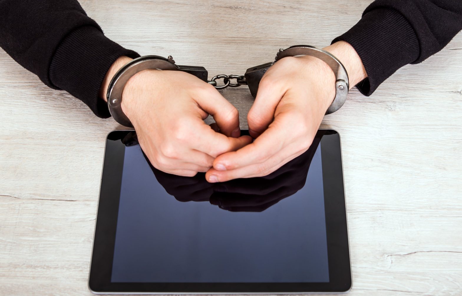 Person in Handcuffs with a Tablet on the table. News - tablets for inmates, Hall County jail