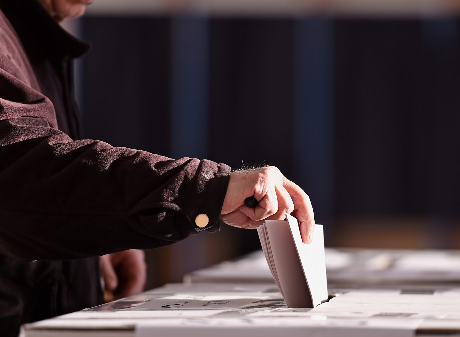 A person casting vote into the the ballot box. News - Michigan to implement automatic voter registration for released prisoners in 2025