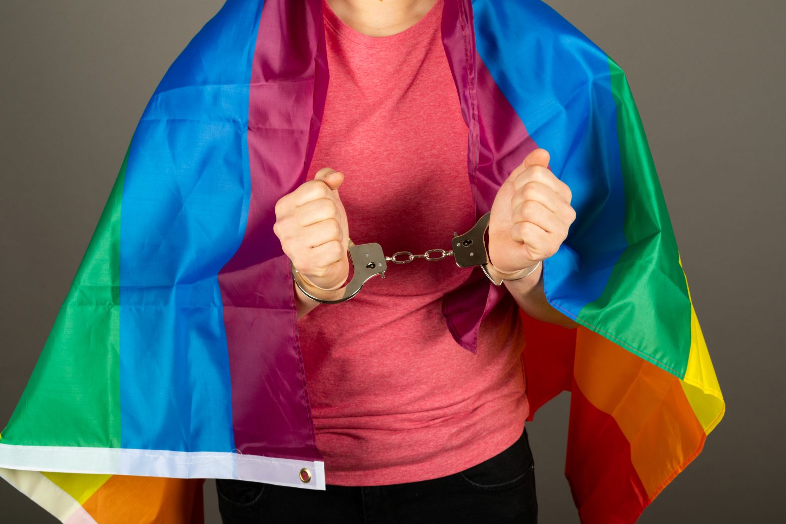 A gay man in handcuffs wearing a rainbow flag. News - Georgia pressed to fund gender transition for a prisoner