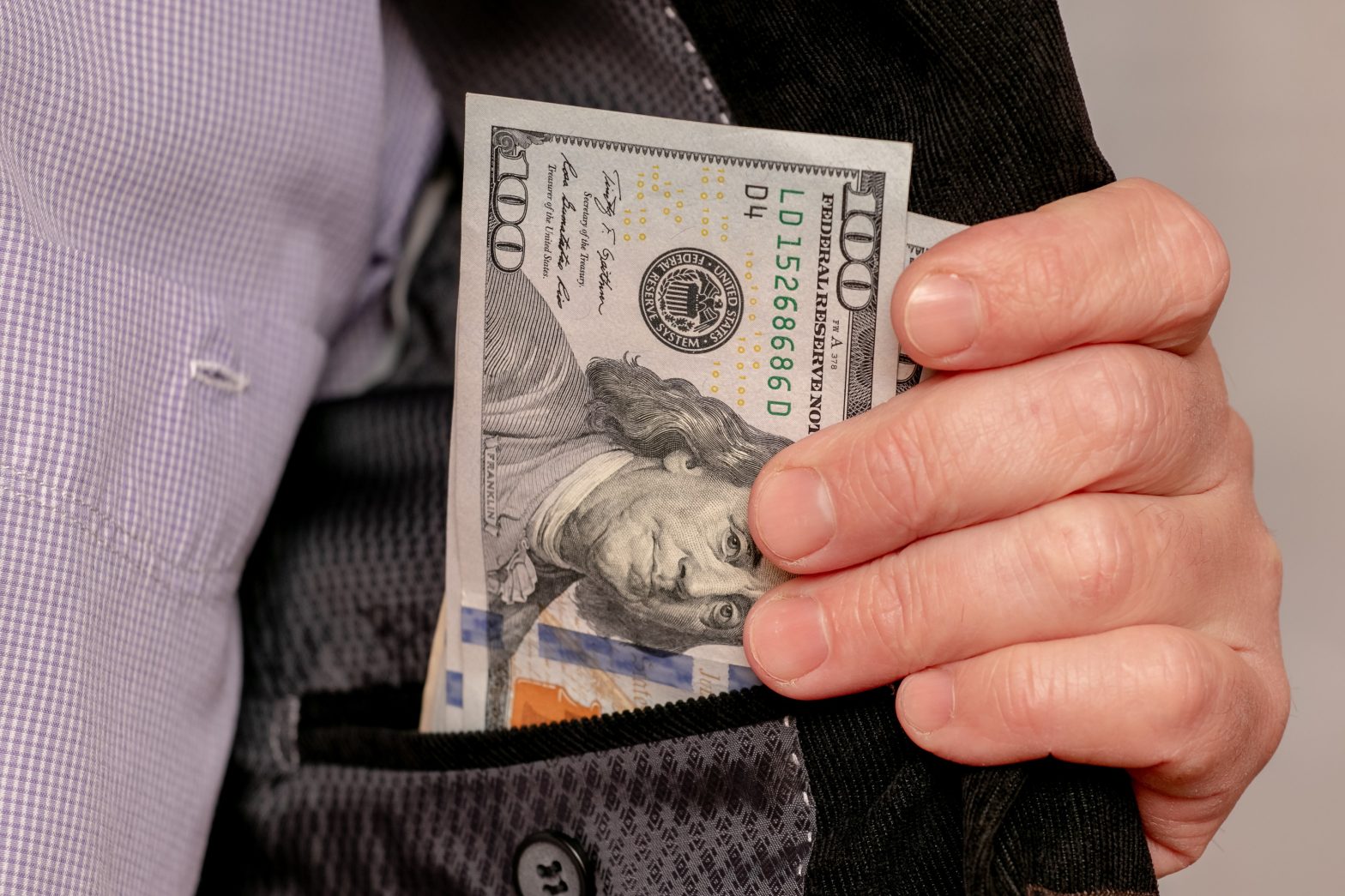 A man showing money hidden in his inner pocket. News - Quandelle Joseph Guilty Plea, MDC Brooklyn Bribery